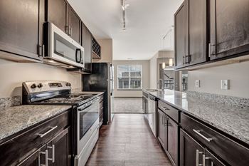 A modern kitchen with dark wood cabinets and granite countertops.
